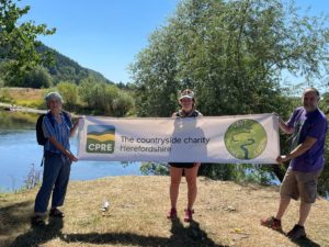 Sophie and friends standing with our banner at the conflence of the rivers