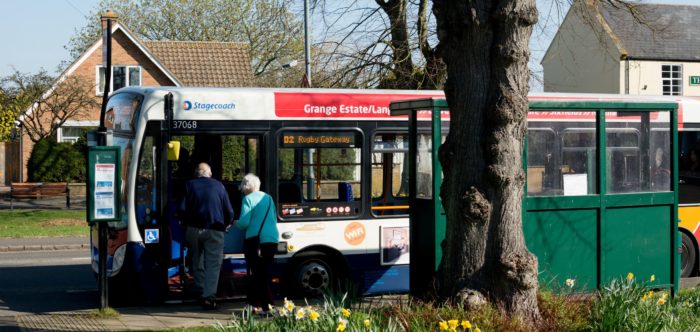 People boarding a bus in a rural village in springtime