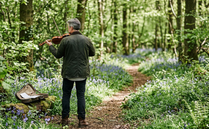 image of a man playing a violin in a wood filled with bluebells